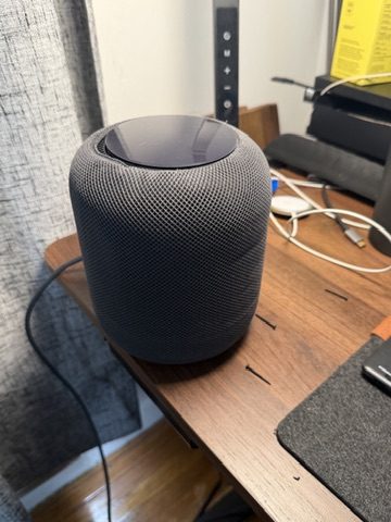 A space grey first-generation HomePod on a walnut table, fully reassembled.